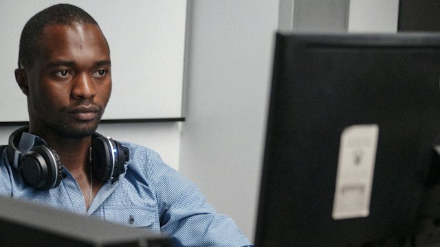 IT professional with headphones monitoring systems at a workstation